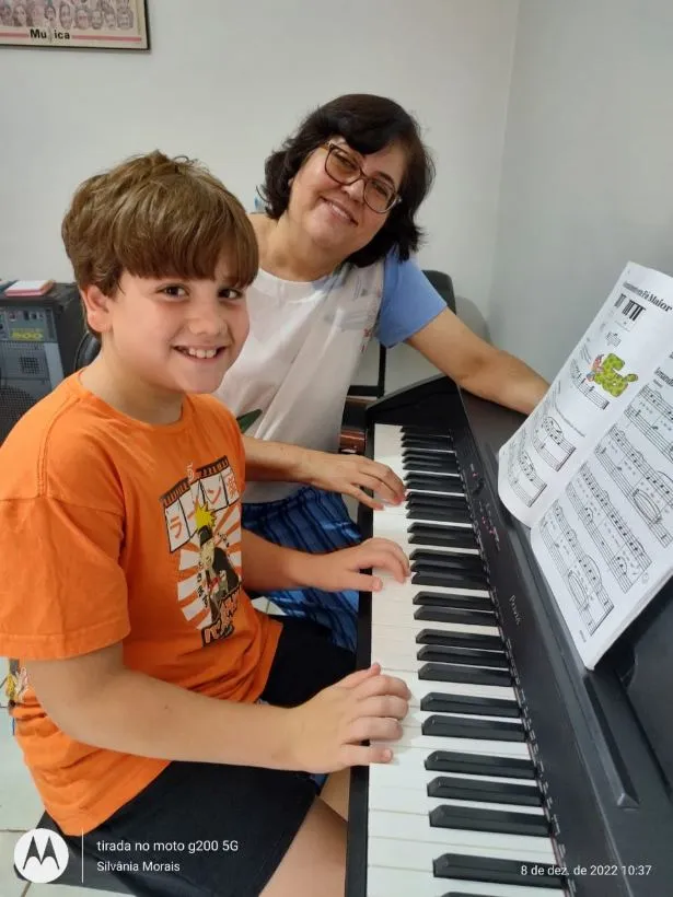 Menino aprendendo piano ao lado da professora na Spasso Musical