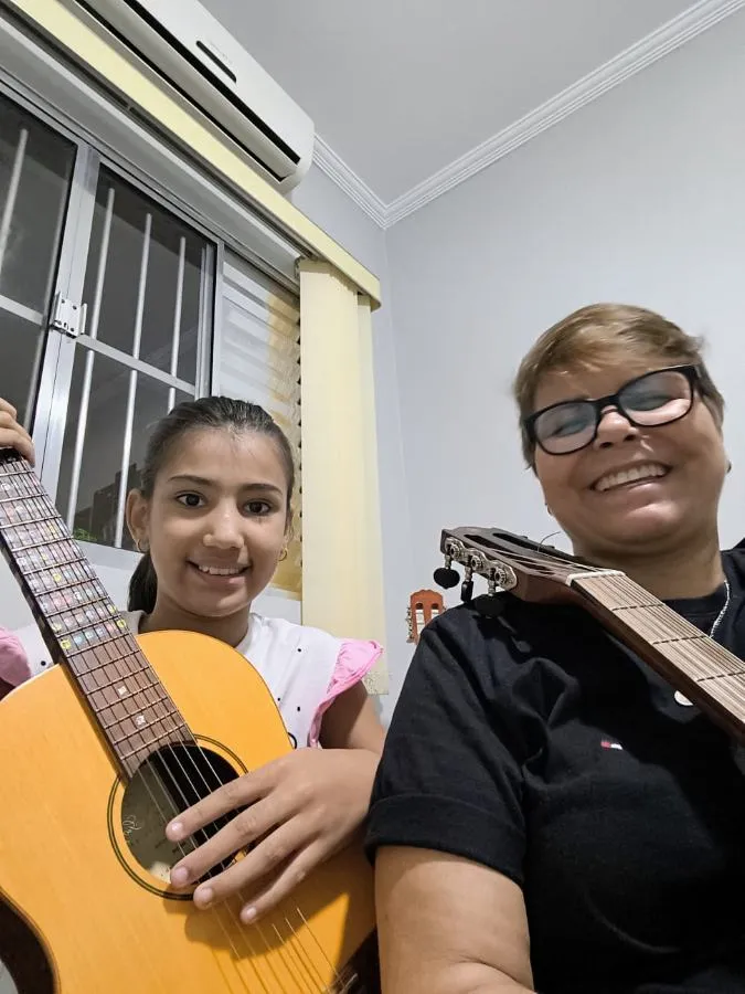 Criança aprendendo violão com a professora na Spasso Musical